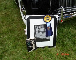 DSC05762 Blue ribbon for "Best Prewar Open Car" on photo of Doris Duke with 1938 Packard Landaulet By Rollston in the background. 2009 Concours d'Elegance, Newport,...